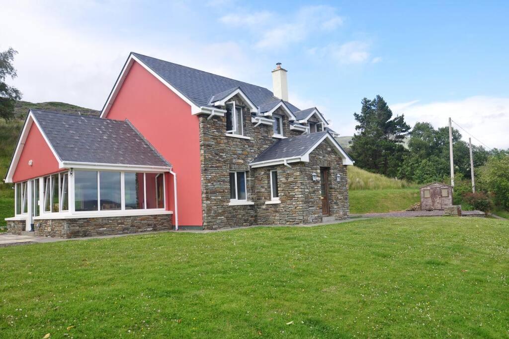 a house with a red roof on a green field at Grace's Landing in Sneem