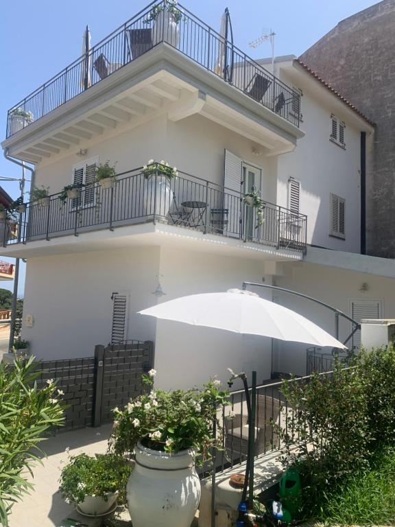 Casa bianca con balcone e ombrellone di Il Fiore Bianco a Capo dʼOrlando