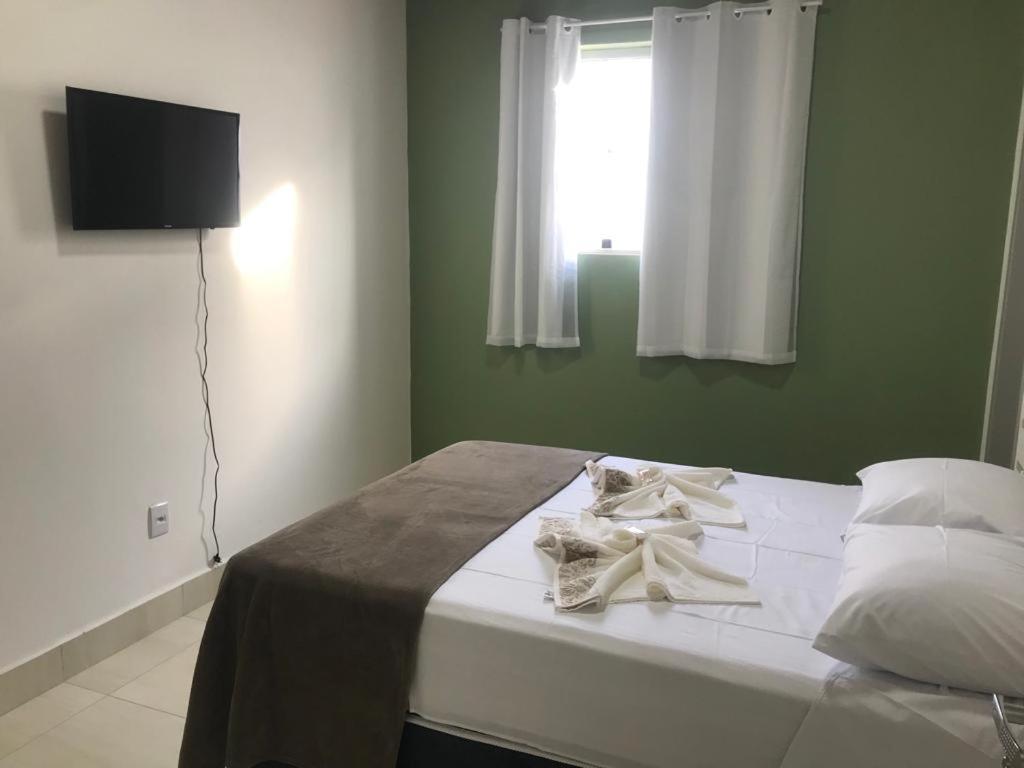 Schlafzimmer mit einem Bett mit weißer Bettwäsche und einem Fenster in der Unterkunft Pousada Salomão in Teixeira de Freitas
