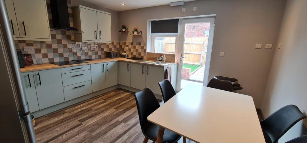 a kitchen with white cabinets and a table and chairs at Enchanting Escape Castle Vale in Minworth