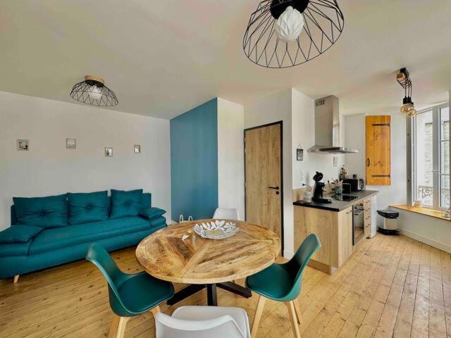 uma sala de estar com um sofá azul e uma mesa e cadeiras em LE POLE CHERBOURGEOIS em Cherbourg en Cotentin