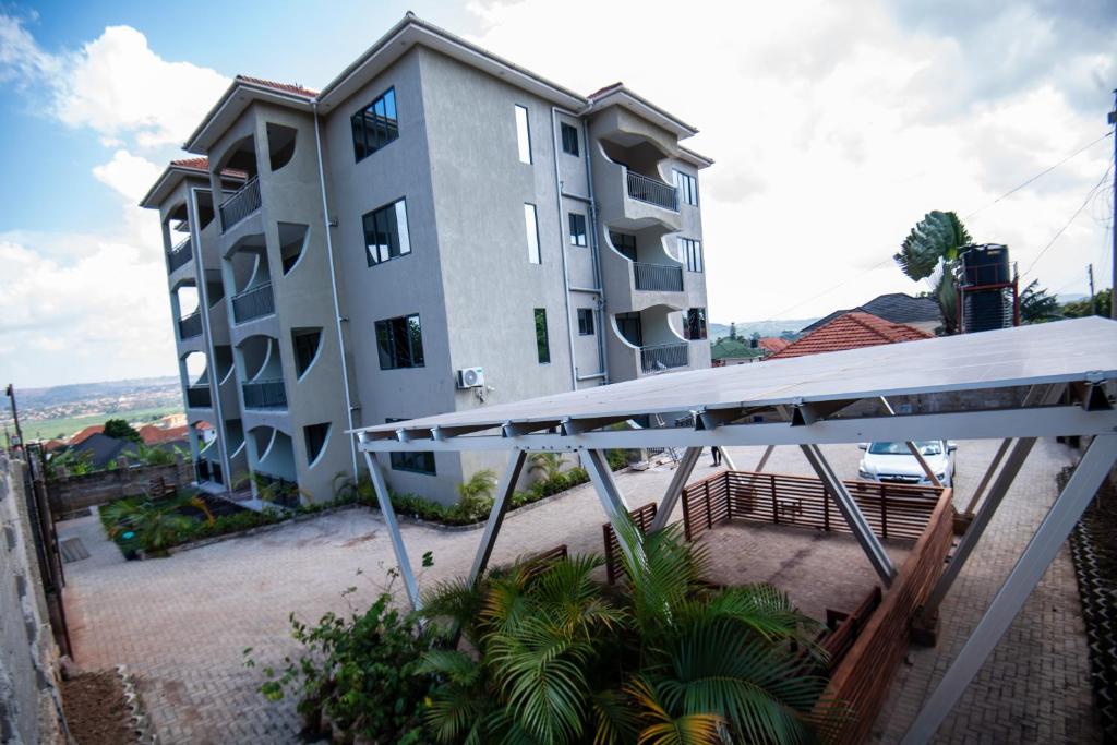 Lubowa View Apartments في كامبالا: عمارة سكنية كبيرة أمامها مظلة بيضاء