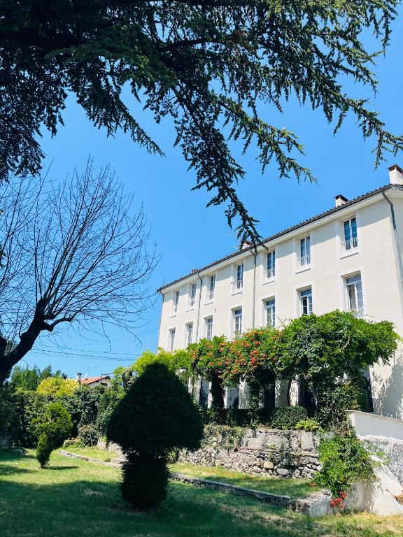 un grand bâtiment blanc avec des arbres devant lui dans l'établissement Les Glycines, charmant studio au calme dans bâtisse de Maître proche du centre ville parking gratuit, à Digne-Les-Bains