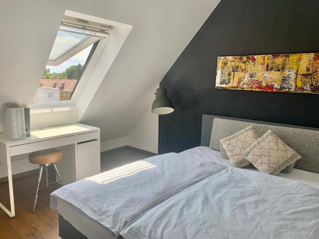 1 dormitorio con cama, escritorio y ventana en Schöne Dachgeschoss-Maisonette Wohnung, en Múnich