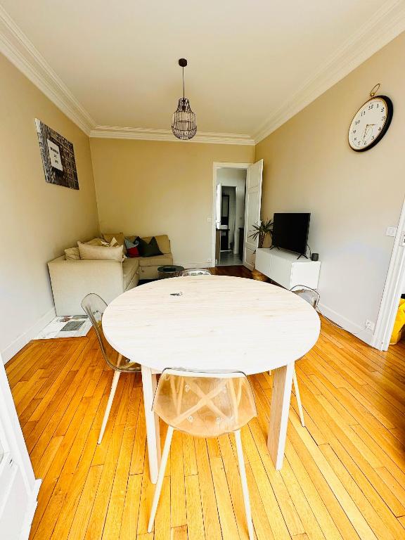 a living room with a table and a clock on the wall at Cosy appartement avec vue Tour Eiffel in Paris