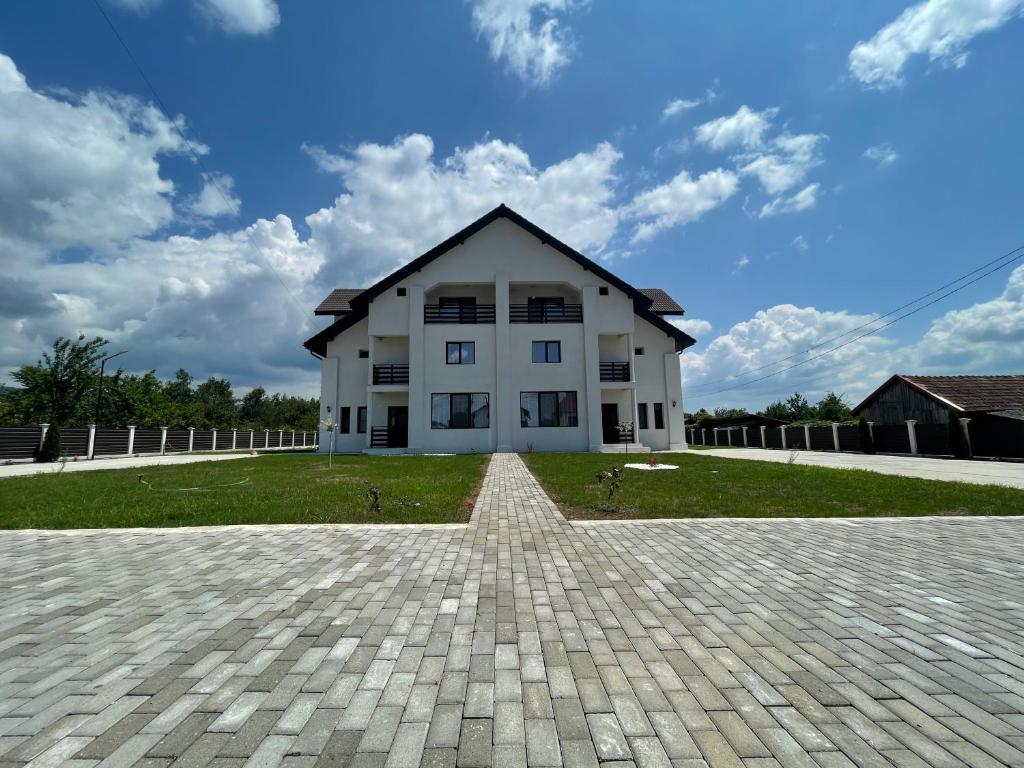 a large white house with a brick driveway at La Scoabă in Baia de Fier