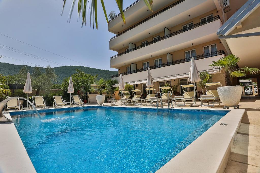 a pool in front of a hotel with chairs and umbrellas at Villa La Vida in Budva