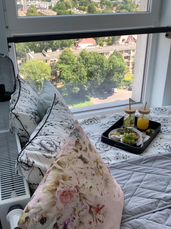 a bed with pillows and a tray of food in front of a window at Panorama View of Krakow in Kraków