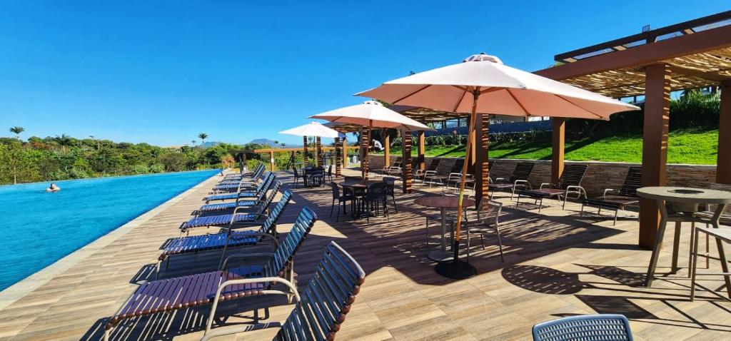 a row of chairs and umbrellas next to a pool at Eco Resort QUINTA SANTA BÁRBARA in Pirenópolis