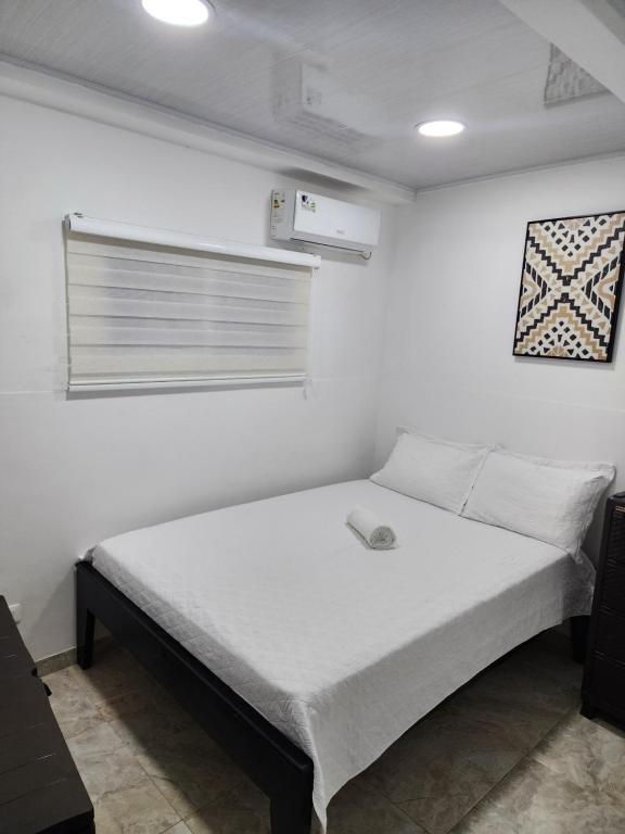 Cama en habitación con pared blanca en Apartamento Turistico Soul en La Loma