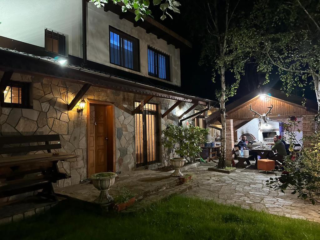 a stone house at night with people sitting in the yard at Vila Belashtitsa in Belashtitsa