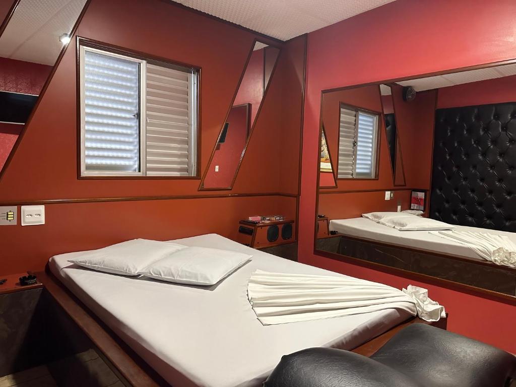um pequeno quarto com uma cama e um espelho em Motel Cigano’s em Belo Horizonte