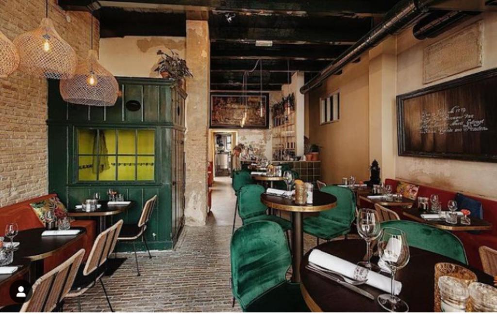 a restaurant with green chairs and tables in a room at Bed bij Bistro in Medemblik