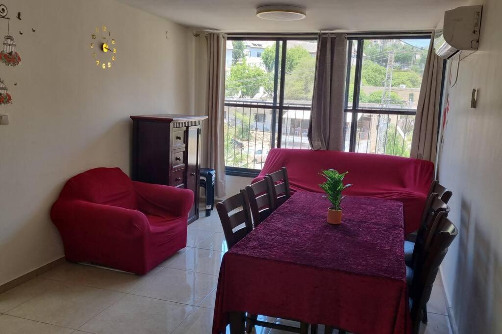 a living room with a table and a red couch at הבית בפיקא. צמוד לרמבם in Tiberias