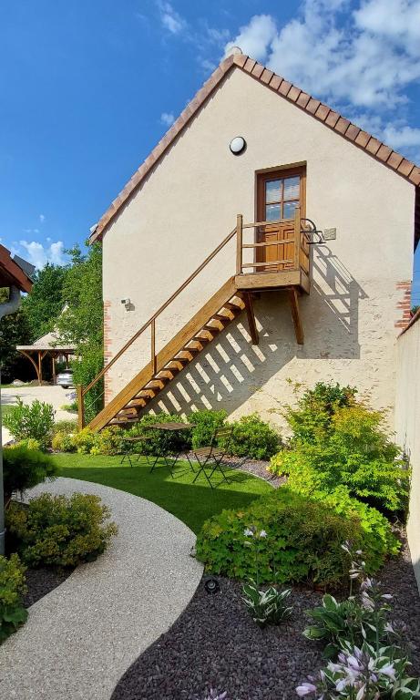 a house with a wooden staircase on the side of it at Appartement T2 Le bief des jardins in Bracieux