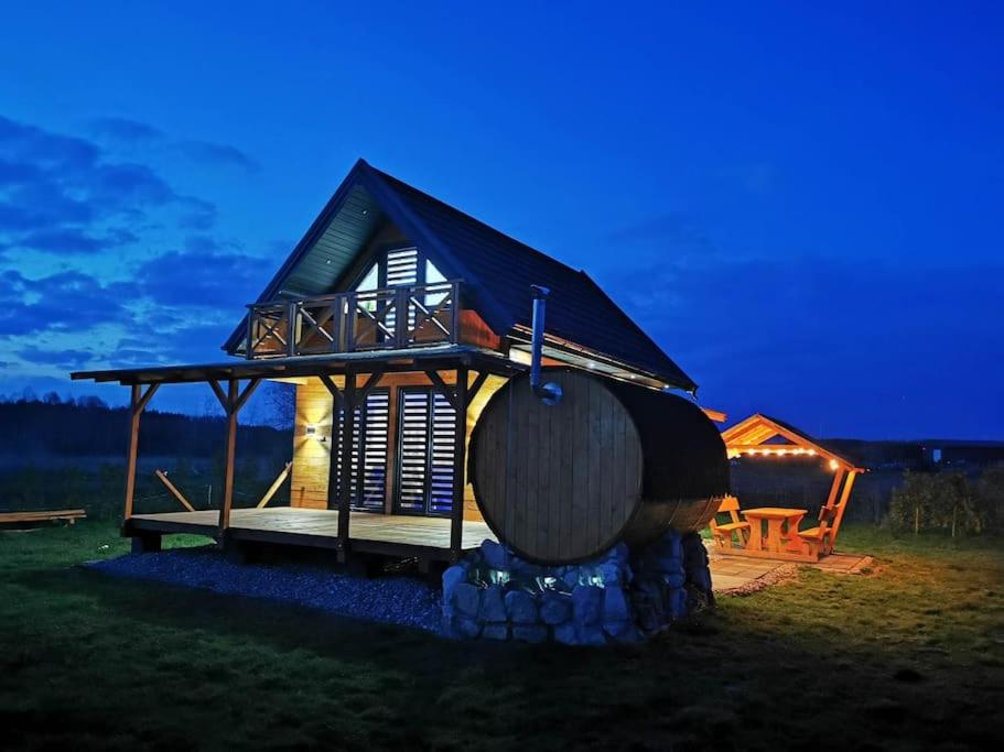 uma pequena cabana com um grande barril na relva em Domek na roztoczu em Tomaszów Lubelski