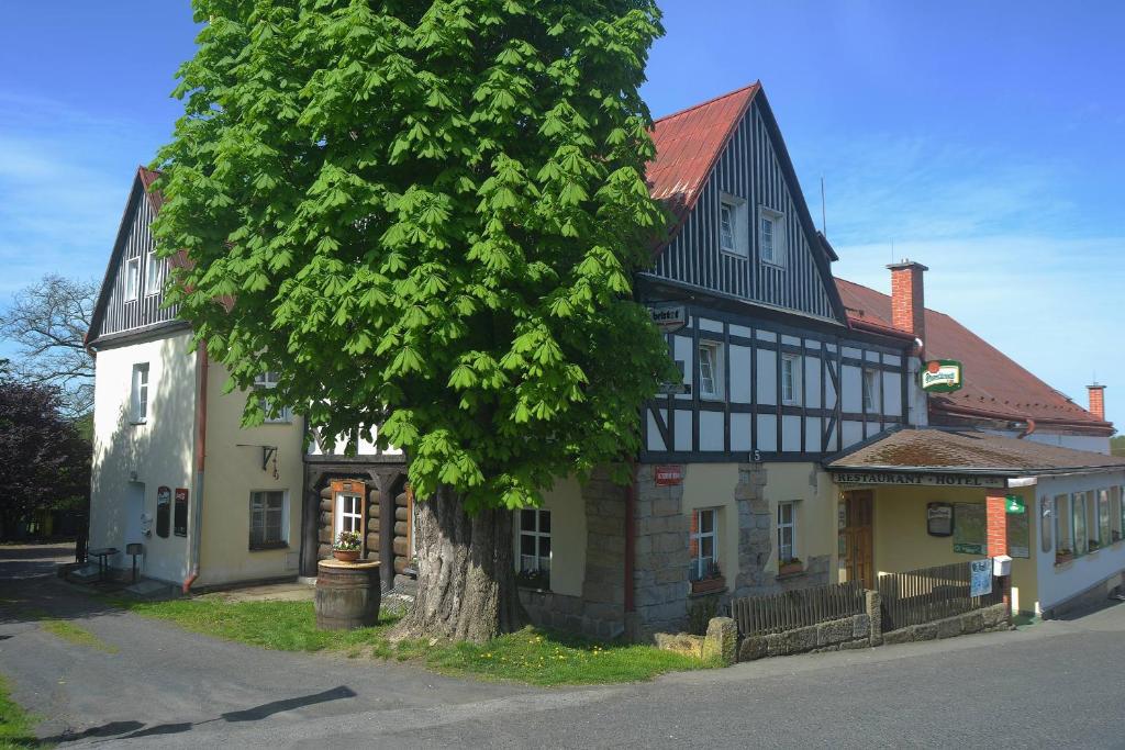 ein großes Gebäude mit einem Baum davor in der Unterkunft Hotel U Zeleného Stromu - Zum Grünen Baum in Hřensko