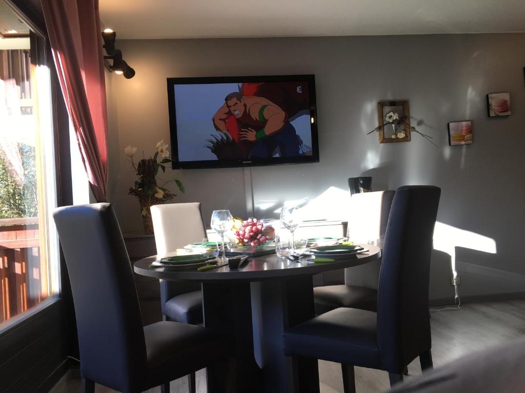 une table à manger avec des chaises et une télévision murale. dans l'établissement Studio Clos des Meurets, à Praz-sur-Arly