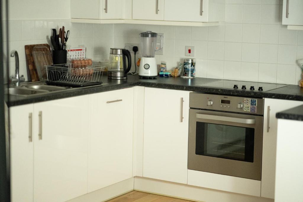 a kitchen with white cabinets and a stove top oven at Repton house in Woodford