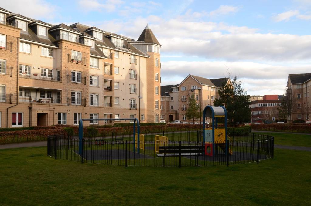 un parque infantil en un parque frente a un edificio en Powderhall Riverside, en Edimburgo