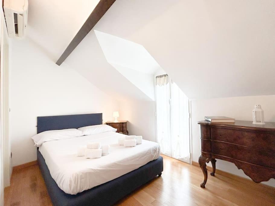 a bedroom with a white bed and a wooden dresser at [Elegante mansarda] 300mt dal mare - Centro - WiFi in Savona