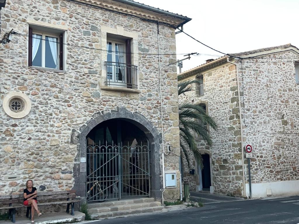 une femme assise sur un banc devant un bâtiment dans l'établissement LOFT-HOLIDAY 3 Appartement spacieux à proximité de la plage, à Pinet