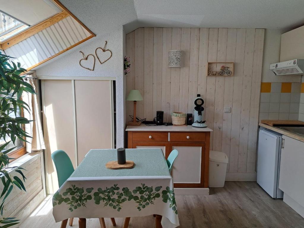 Le Cosy Liberty في Ustou: مطبخ مع طاولة وكراسي في غرفة