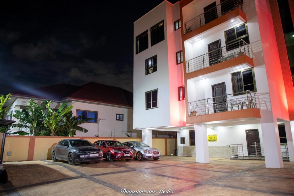 3 auto parcheggiate in un parcheggio di fronte a un edificio di Executive One Bedroom Furnished Apartment in Accra a Accra