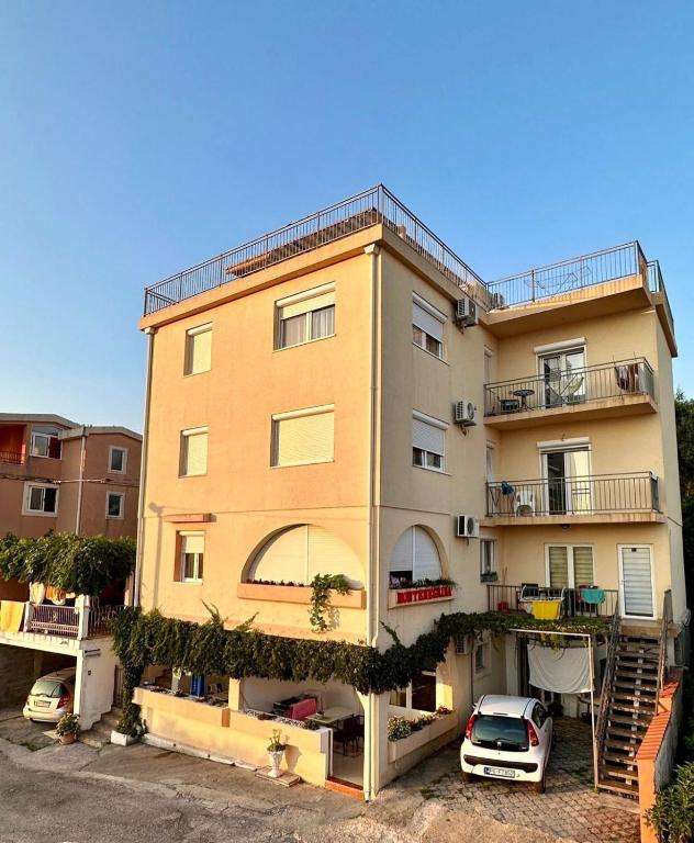 a yellow building with cars parked in front of it at Montenegrina Apartment in Budva