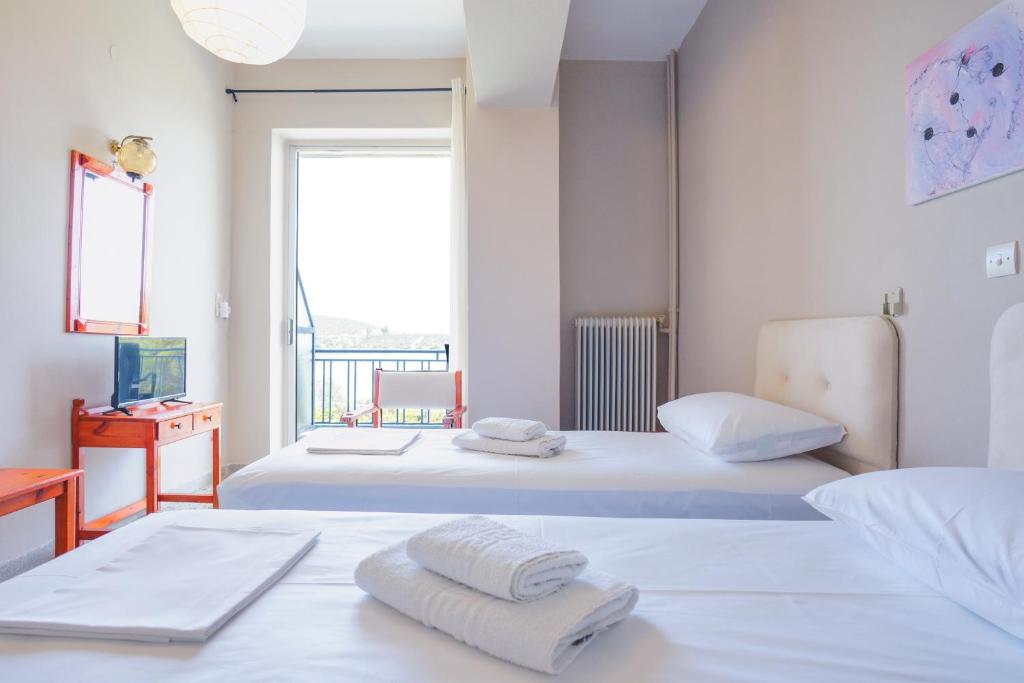 two beds in a room with a window at Hotel Korfos - Ξενοδοχείο Κόρφος Renovated in Korfos