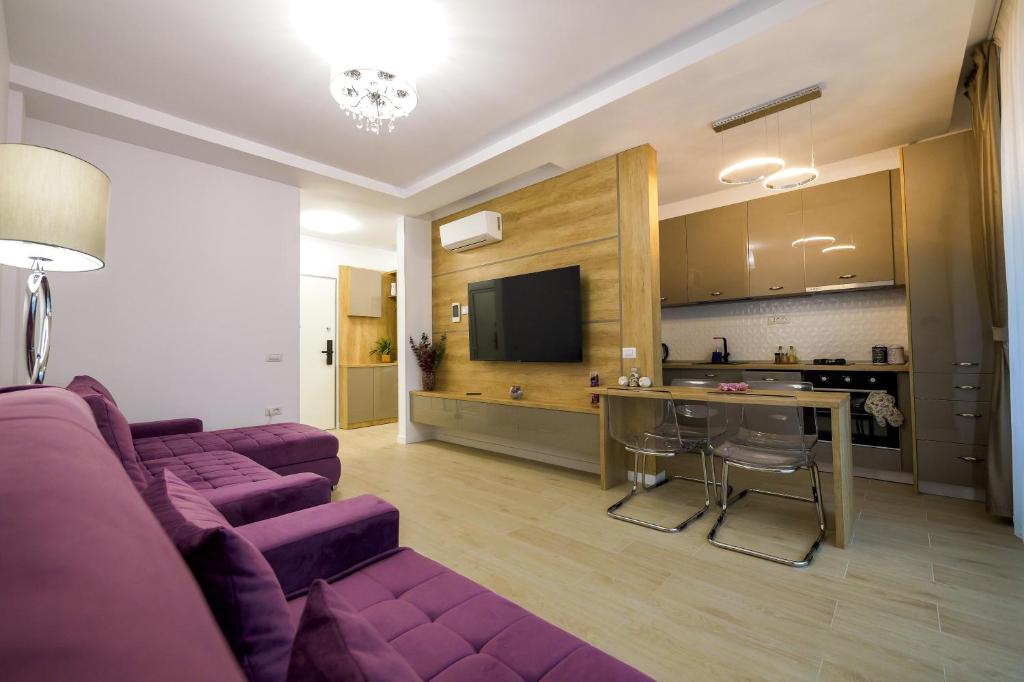a living room with a purple couch and a kitchen at Purple Luxury Apartment Lake On in Mamaia