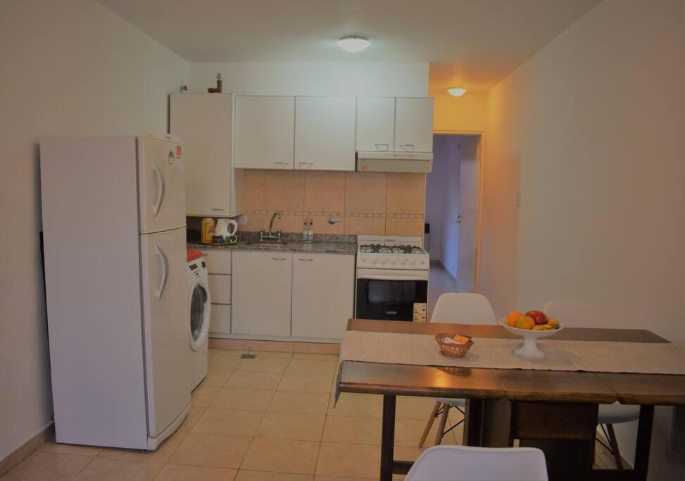 a kitchen with a white refrigerator and a wooden table at Dpto cercano al centro con WIFI in San Luis