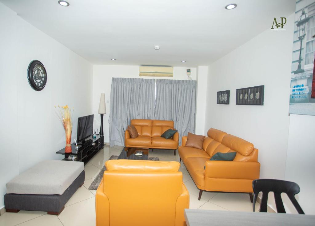 uma sala de estar com dois sofás laranja e uma televisão em Adrich Properties Gallery em Acra
