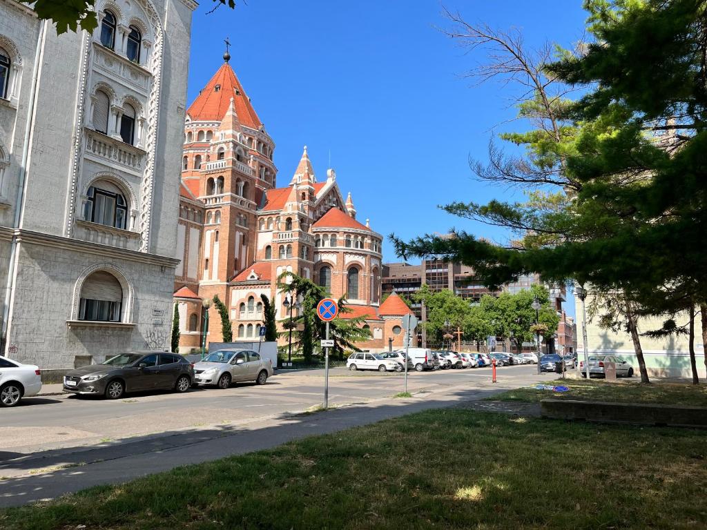 a large building with cars parked in front of a street at Szeged D&oacute;m-Sellőh&aacute;z Apartman in Szeged
