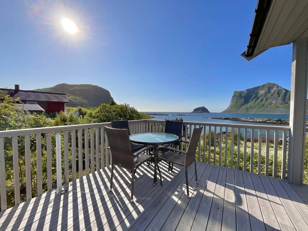 a table and chairs on a deck with a view of the ocean at Mannen Panorama Lofoten in Offersøya
