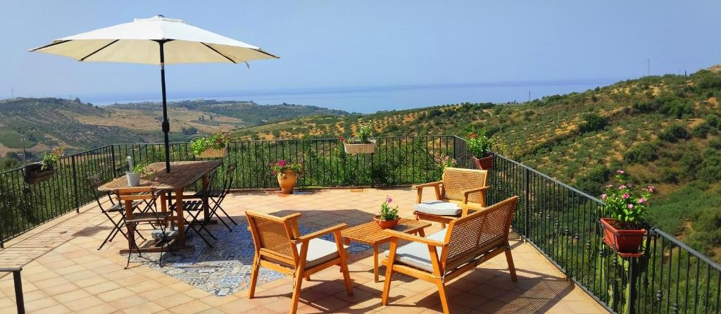 a patio with a table and chairs and an umbrella at villa immersa in oliveto vista mare in Sciacca