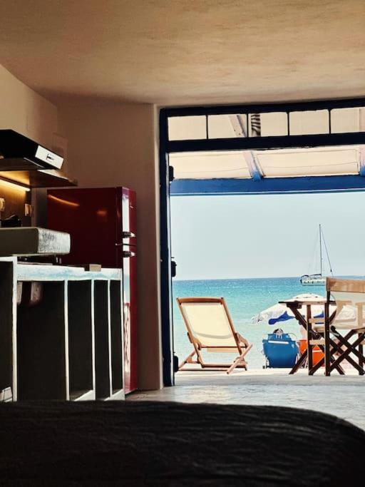 um quarto com vista para uma praia com uma mesa e uma cadeira em Cave Beach House Milos em Provatas