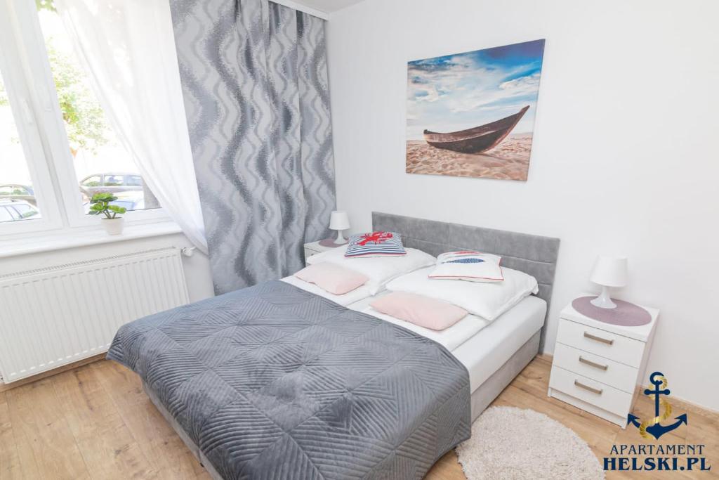 een slaapkamer met een bed en een foto van een boot bij Apartament Helski in Hel