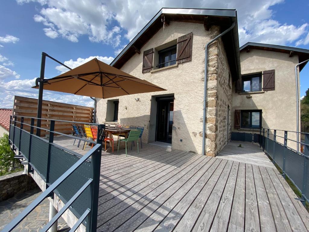 a wooden deck with a table and an umbrella at Gîte au cœur des Gorges de la Loire in Aurec-sur-Loire