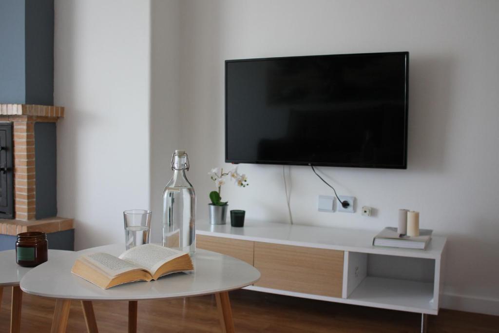 un soggiorno con TV e tavolo con libri di Blue Side Apartment in Porto Rafti a Porto Rafti