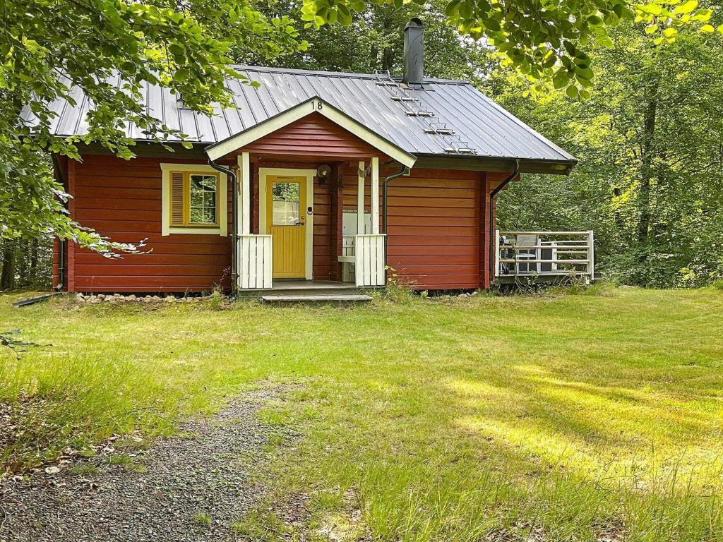 une petite maison rouge avec une porte jaune dans une cour dans l'établissement 4 person holiday home in HJ RNARP, à Hjärnarp