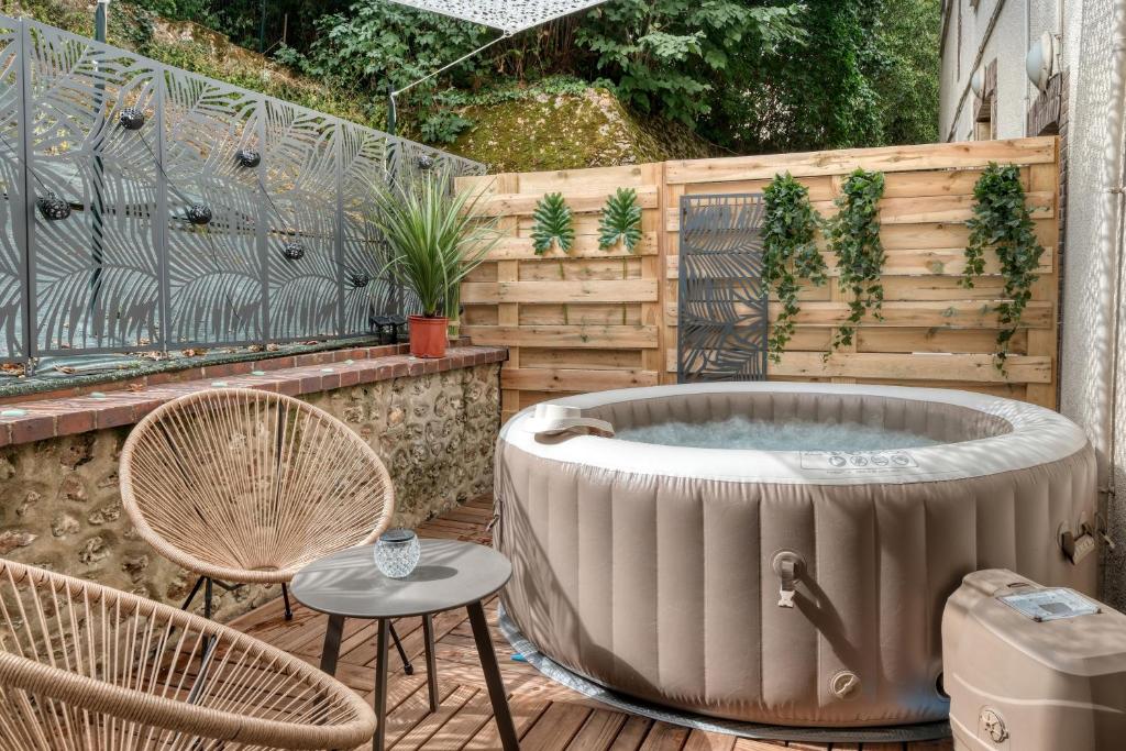 a hot tub on a deck with two chairs and a table at Superbe 2 pièces avec Jacuzzi privatif face Gare Proche Cathédrale in Chartres