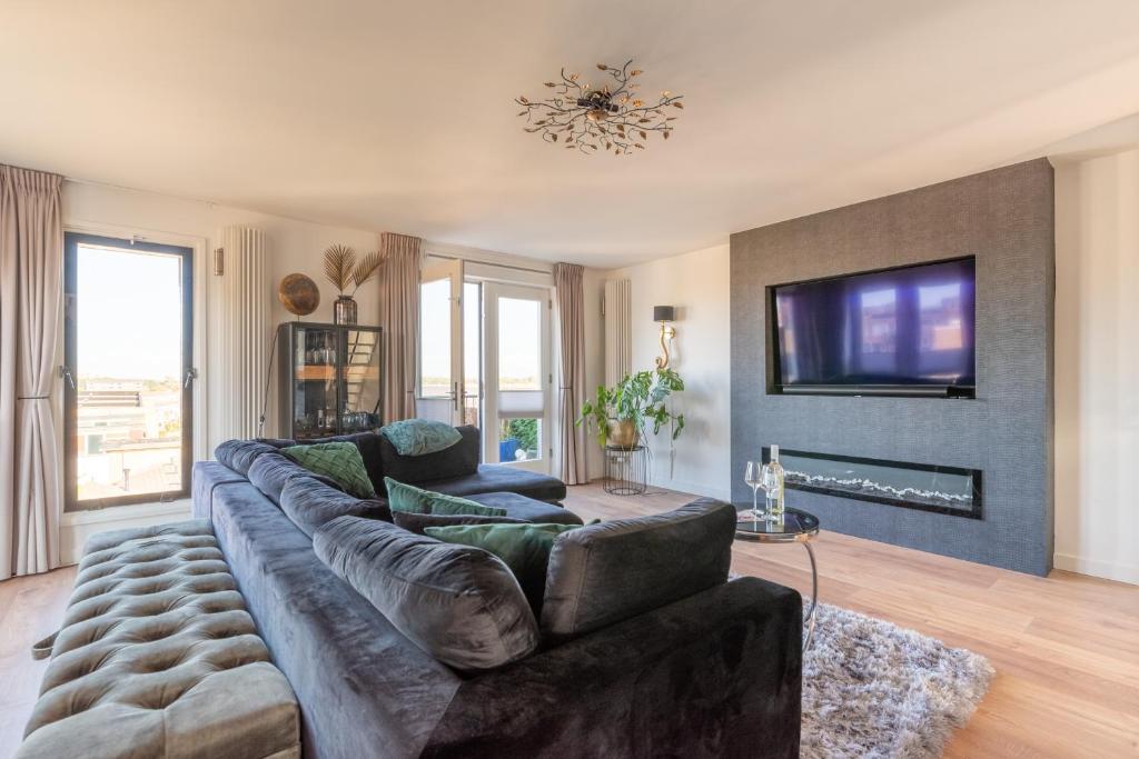 a living room with a large couch and a tv at Beach Villa & Studio in Zandvoort