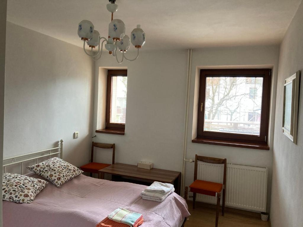 a bedroom with a bed and a table and two windows at U starkych in Poprad