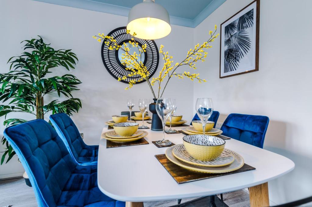 a dining room with a white table and blue chairs at Newly Refurbished 3 Double Bedroom Knowsley Liverpool Townhouse in Knowsley
