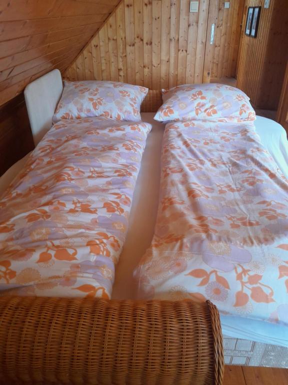 een bed en kussens in een kamer met een rieten stoel bij VÁRBALOG in Várbalog