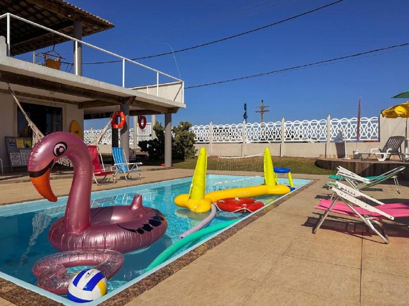 een zwembad met verschillende opblaasbaar speelgoed erin bij Suítes Pé Nareia Itaipuaçu in Maricá