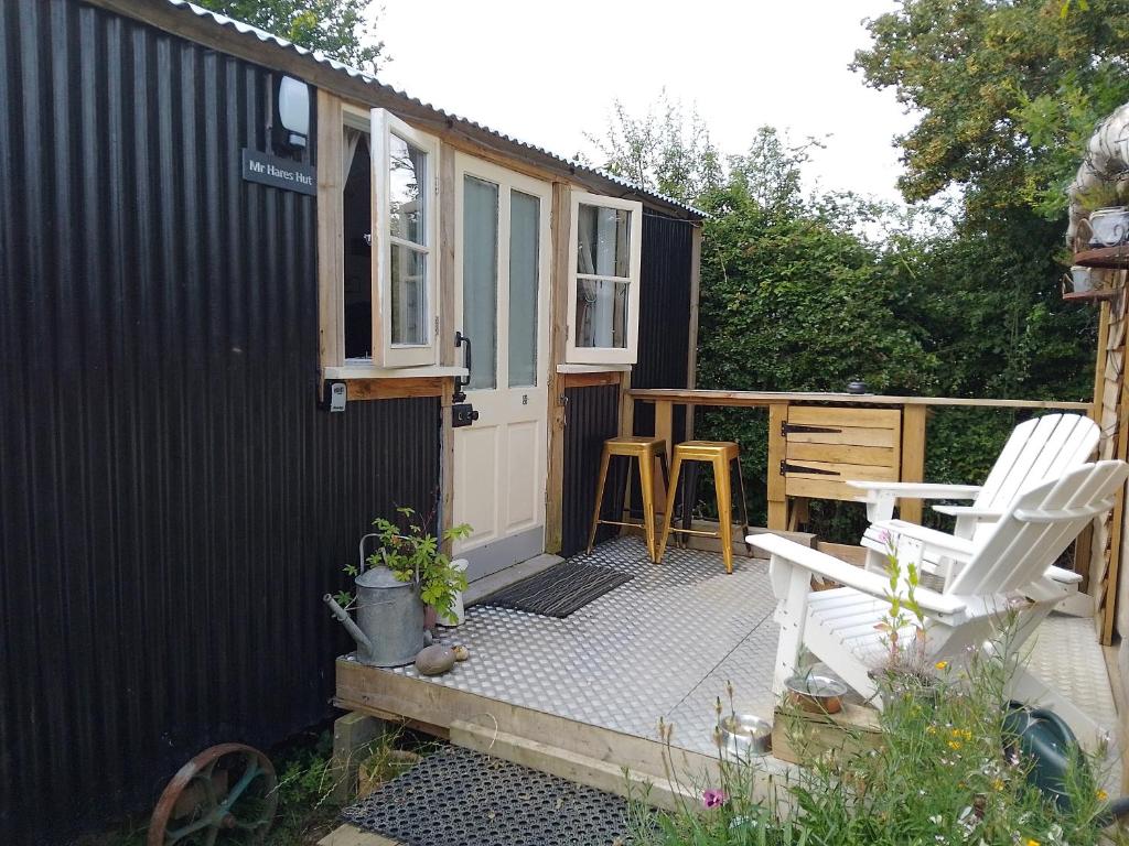 a small black shed with a white door and a patio at Mr Hares shepherd hut in Mellis