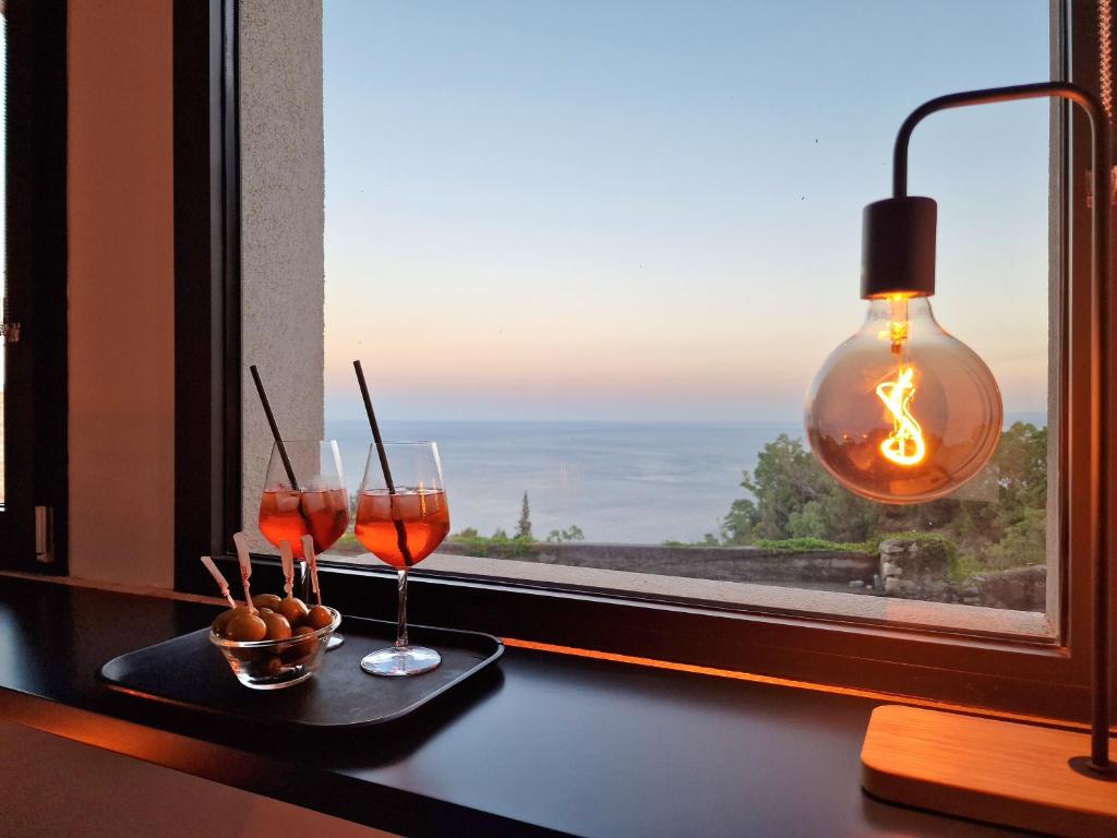 una finestra con due bicchieri da vino su un tavolo con vista di The White Domus a Taormina