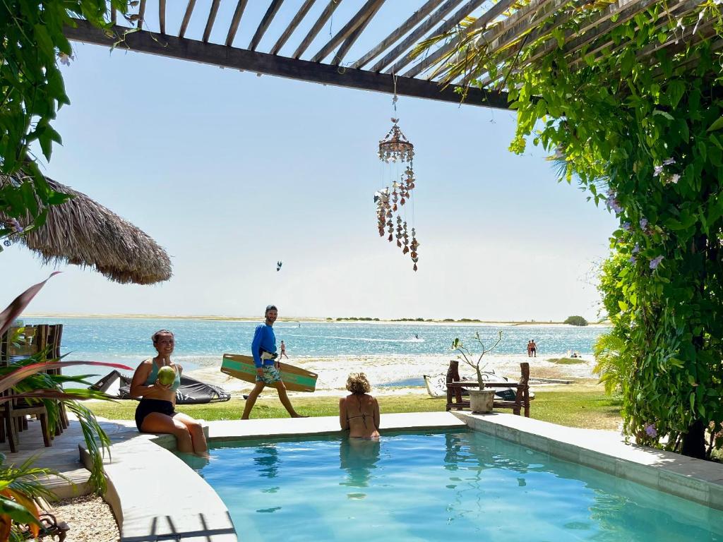 a group of people sitting around a swimming pool next to the beach at Coco-Knots Kite - Ilha do Guajiru in Itarema